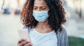 Woman looking at her phone while wearing a face covering.