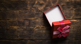 Small, open gift box on a wooden surface.