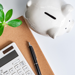 Piggy bank, calculator and notebook on a desk.