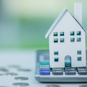 Paper model of a house placed on top of a calculator.