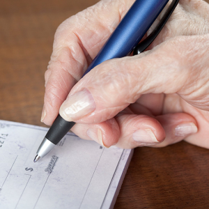 Senior woman writing a cheque.