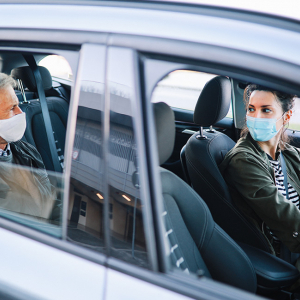 Woman driving a rideshare car with a male passenger in the backseat