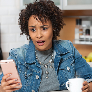 Woman looking at her phone with a shocked expression.