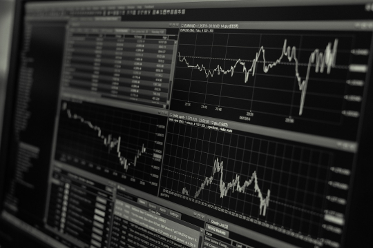 Charts and graphs on a screen depicting market fluctuations.