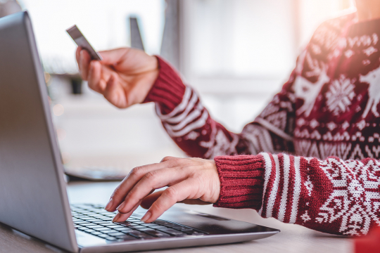 Woman using a laptop and holding a credit card to make an online purchase.