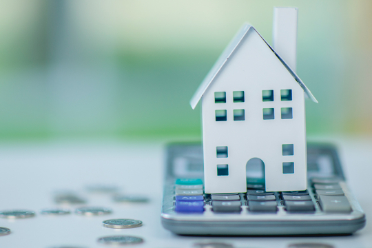 Paper model of a house placed on top of a calculator.