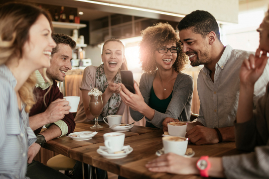 De jeunes adultes en conversation autour de la table d’un café. 