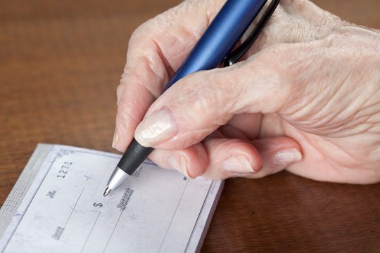 Senior woman writing a cheque.