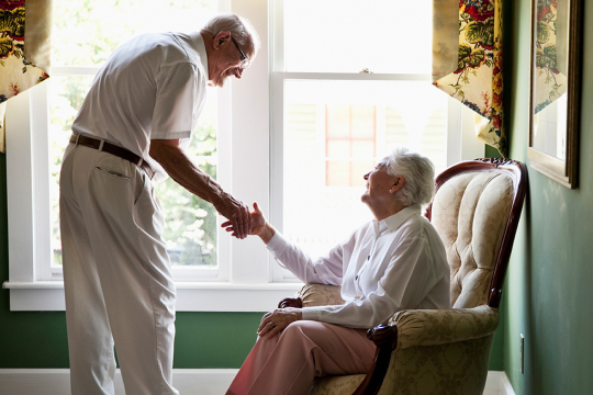 Un couple âgé se tenant la main tout en échangeant un sourire.