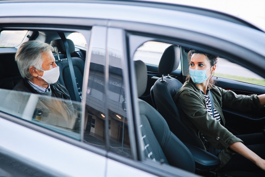 Woman driving a rideshare car with a male passenger in the backseat