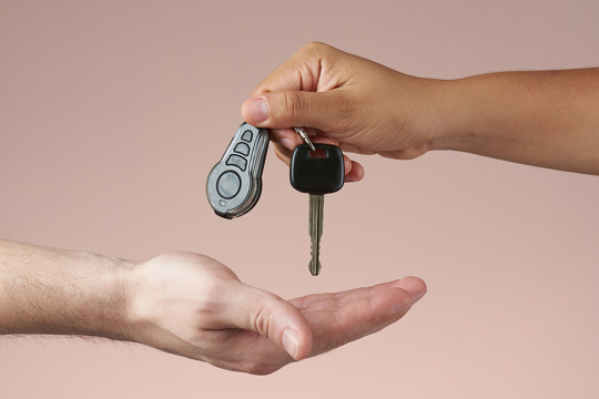 Un adulte passe la clé d’un véhicule dans la main d’une autre personne.