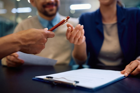 Un couple s’apprêtant à signer un contrat avec un conseiller financier. 