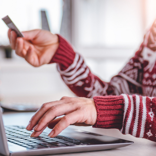 Woman using a laptop and holding a credit card to make an online purchase.