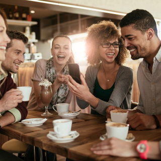 De jeunes adultes en conversation autour de la table d’un café. 