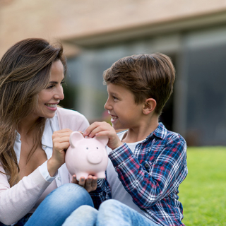 Mother and son putting coins into a piggy bank together.