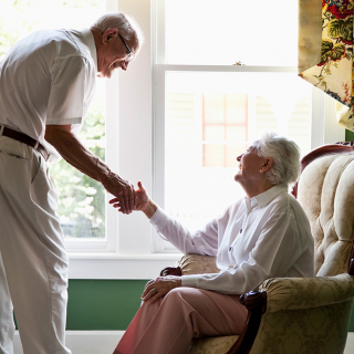 Senior couple holding hands and smiling at each other.