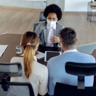 Un jeune couple rencontrant une femme d’affaires dans son bureau.